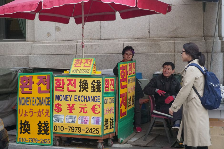 다양한 해외 통화와 트래블 체크카드가 함께 놓여 있는 모습으로, 해외여행 환전 및 결제 수단을 상징합니다.